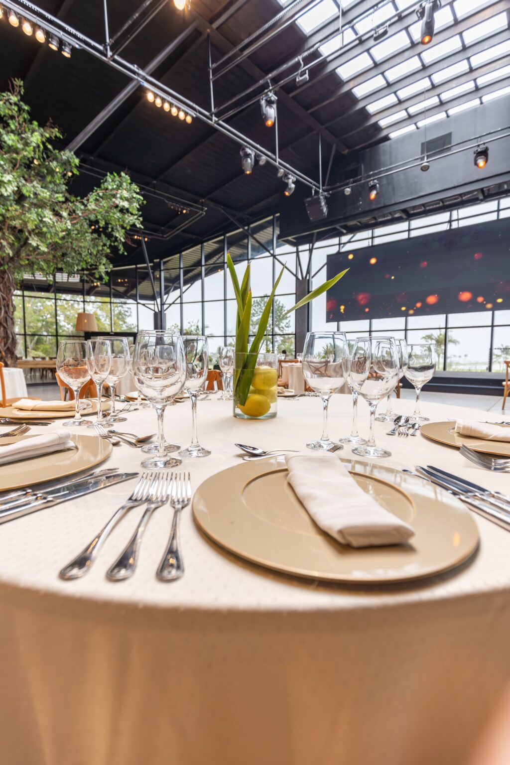 Elegant table setup with glassware and silverware in a modern restaurant hall.