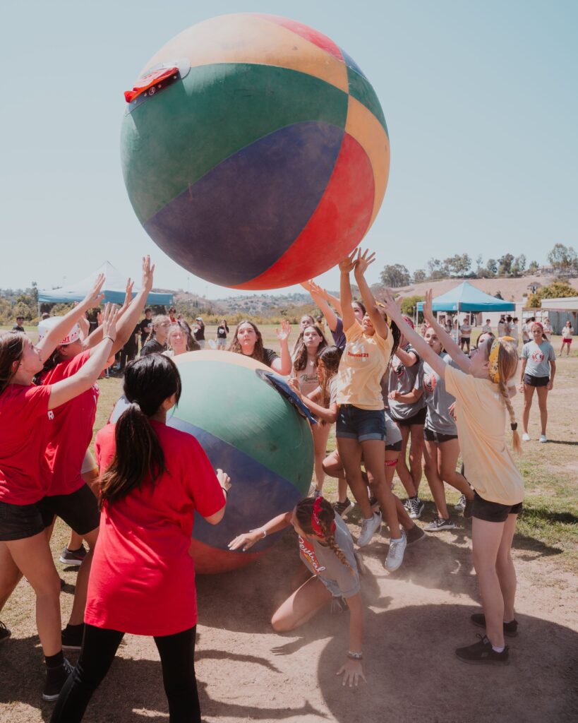 Energetic teenagers enjoy outdoor recreation with giant inflatable balls on a sunny day.
